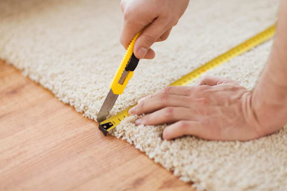 measuring and cutting new carpet in room